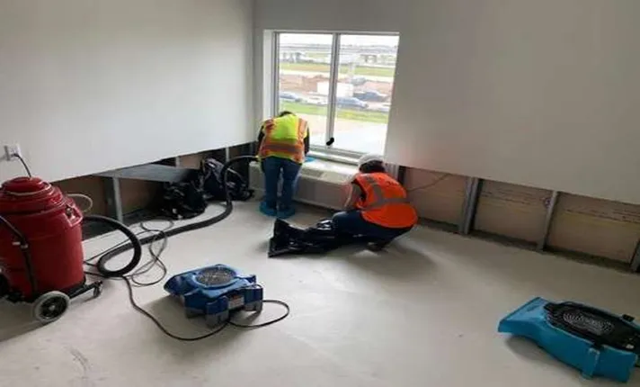 Workers using equipment to clean a room